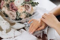 bride-puts-her-hands-table-near-floral-bouquet-shoes-other-bridal-details