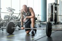 portrait-bald-athletic-man-with-tattoo-his-hand-is-preparing-exercises-with-barbell