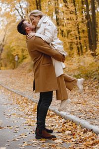 young-man-woman-walking-outside-wearing-beige-coats-blond-woman-brunette-man-autumn-forest-romantic-couple-kissing_1